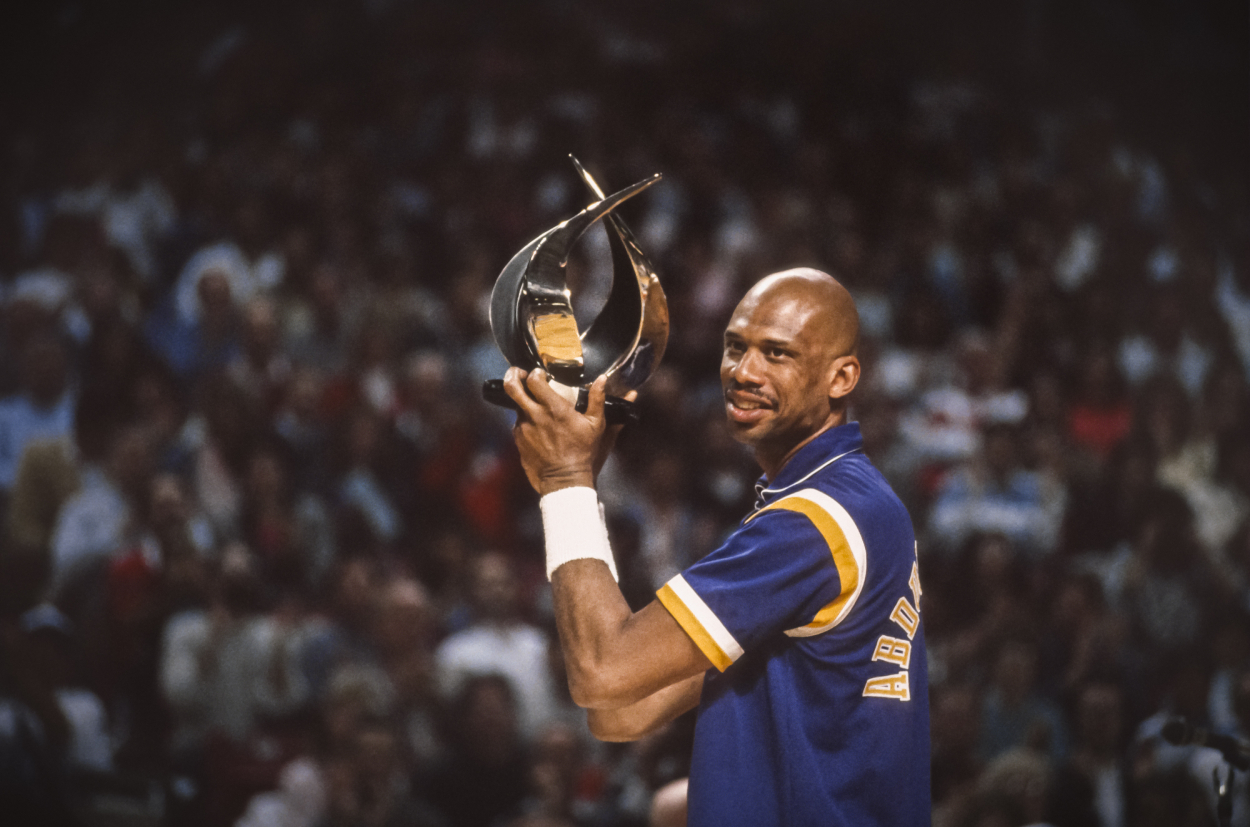 Kareem Abdul-Jabbar of the Los Angeles Lakers holds a trophy before an NBA game.
