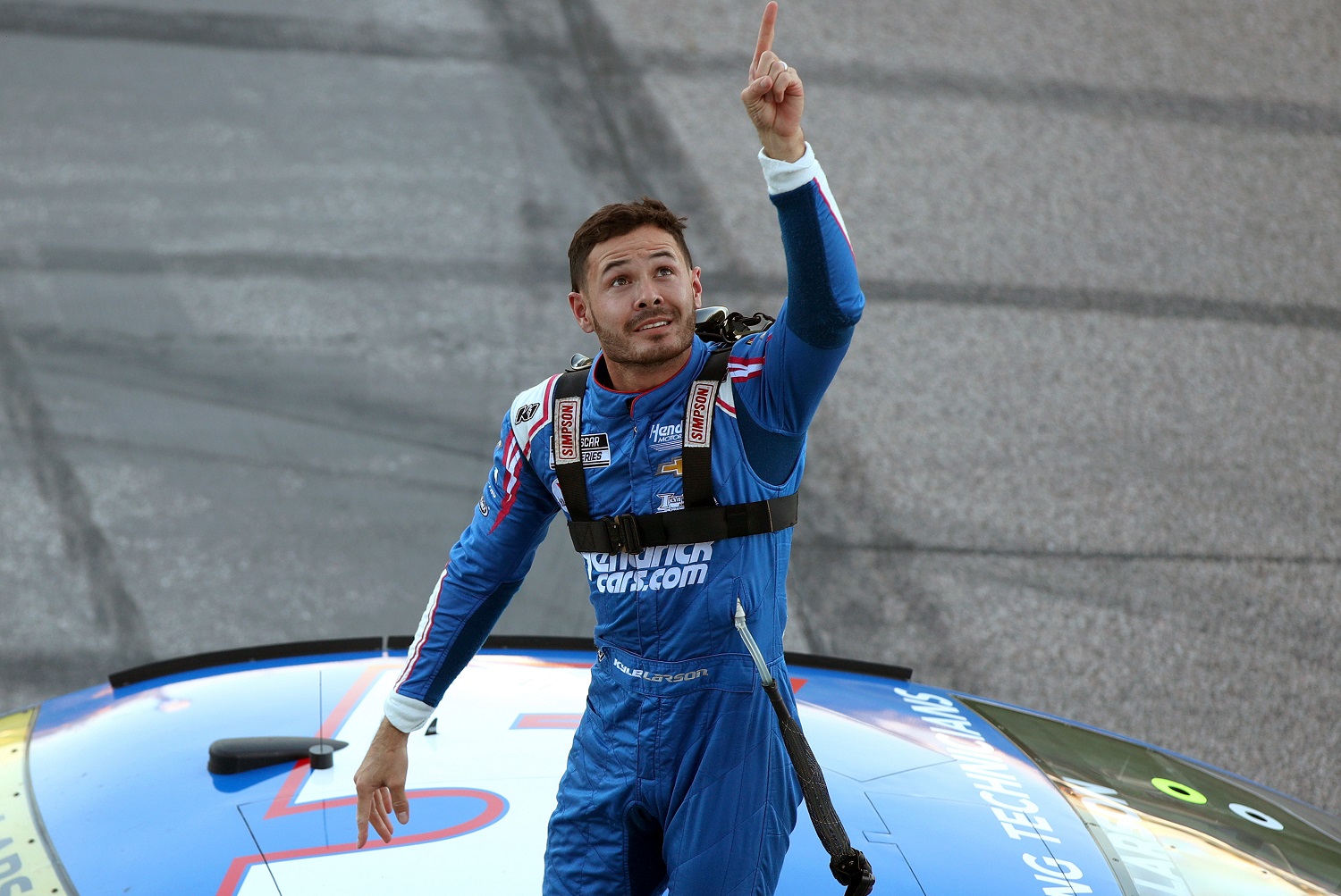 Kyle Larson, driver of the No. 5 Chevy, points toward the sky, as he celebrates winning the NASCAR Cup Series Hollywood Casino 400 at Kansas Speedway on Oct. 24, 2021