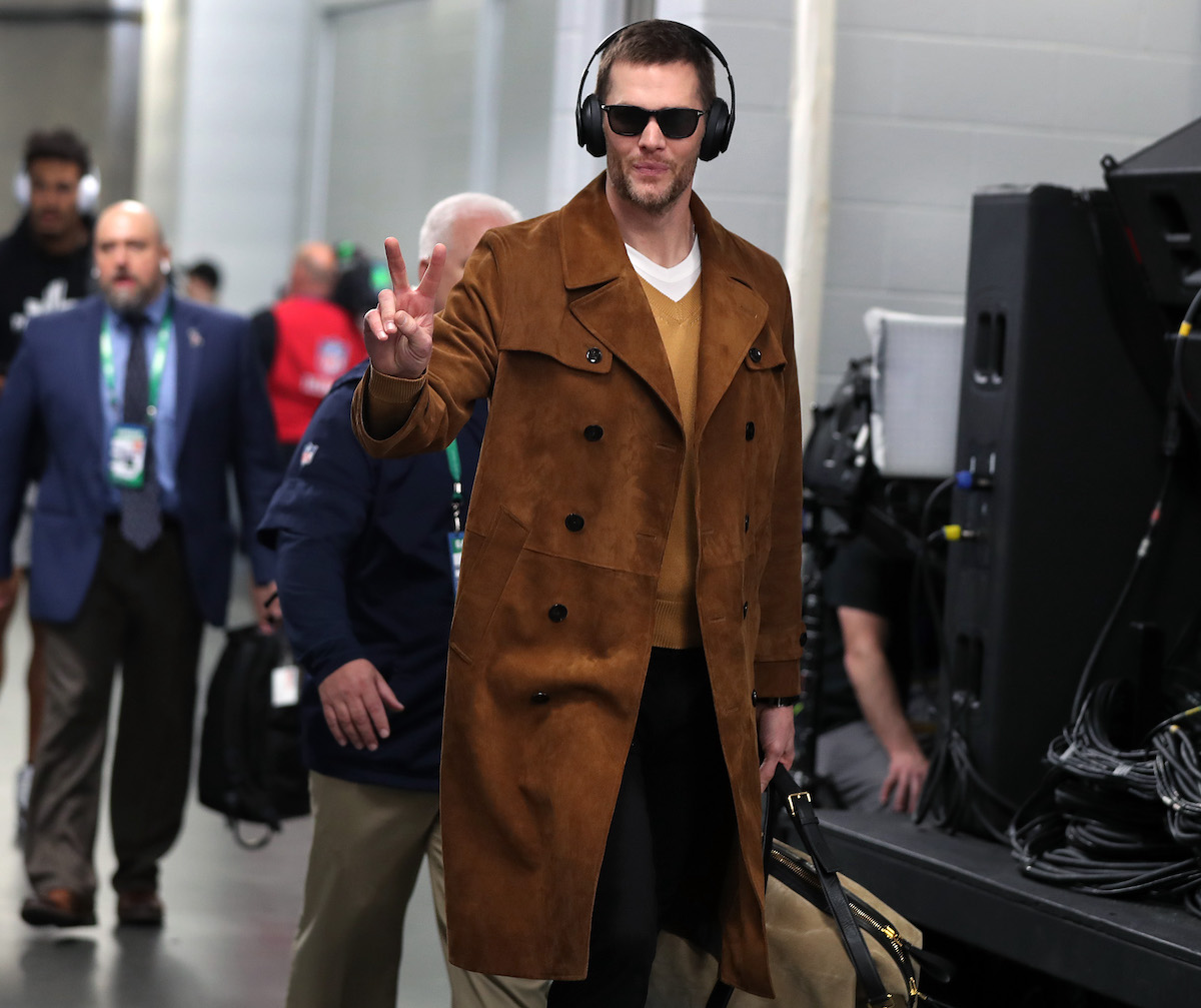 Quarterback Tom Brady flashes a 'V' sign as he and his teammates arrive at the stadium