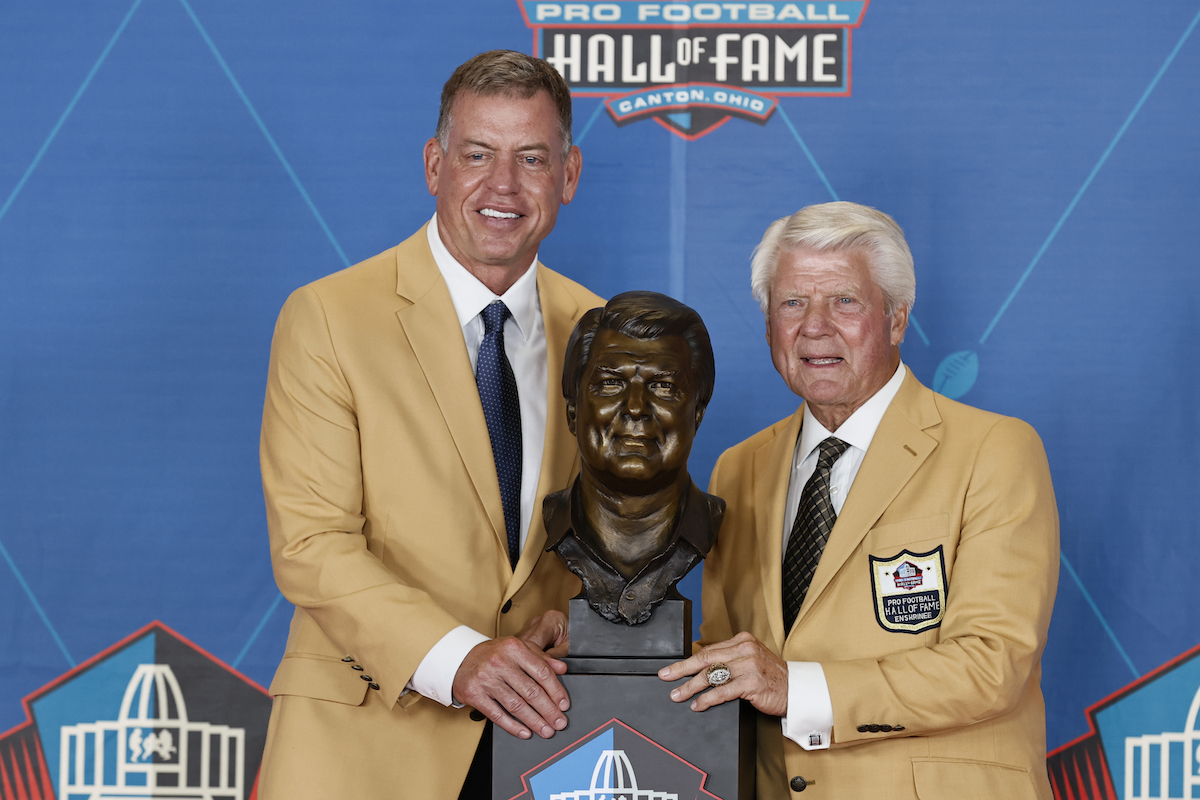 Troy Aikman and Jimmy Johnson pose with the former NFL coach's bust at his Pro Football Hall of Fame induction on August 7, 2021, in Canton, Ohio