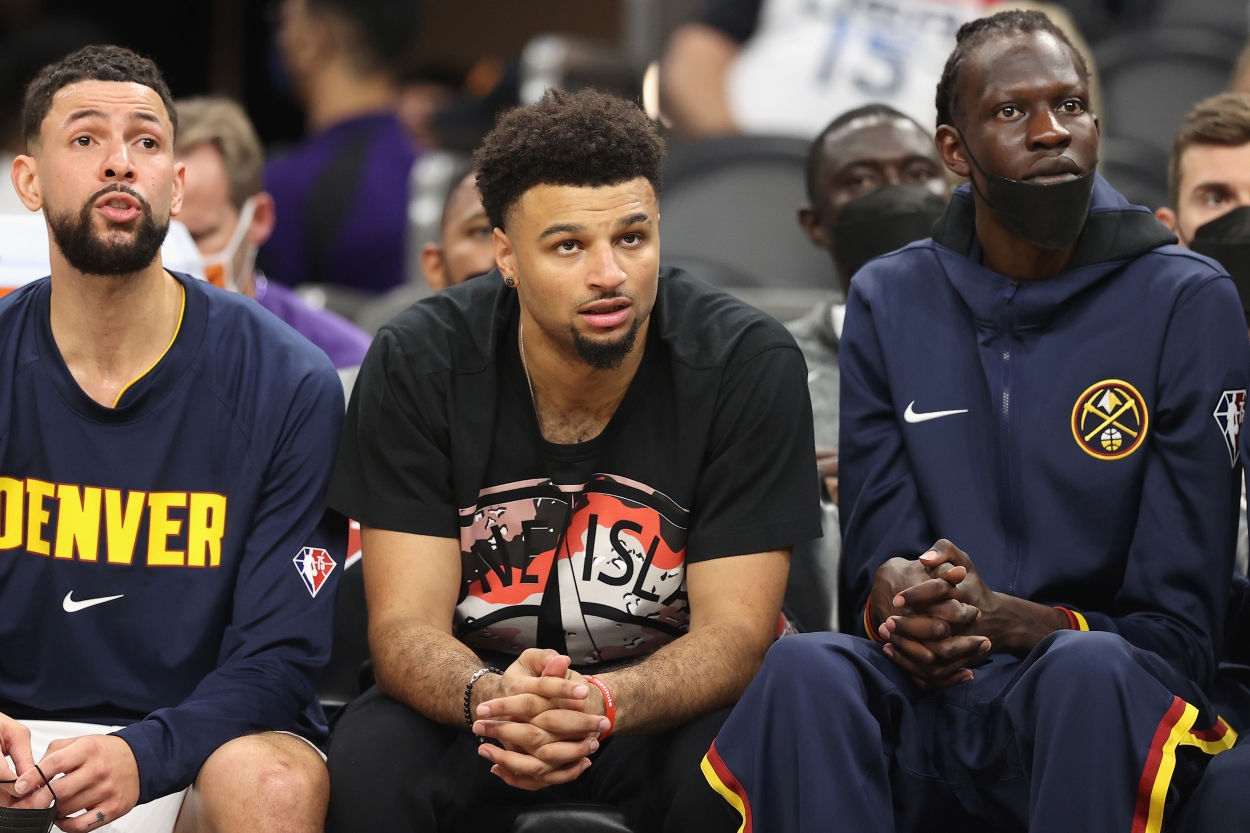Jamal Murray of the Denver Nuggets sits courtside in street clothes during an NBA game.