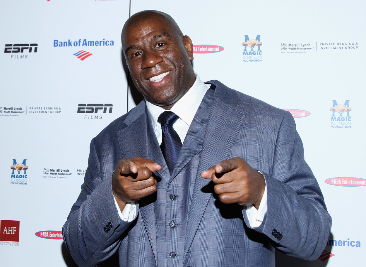 NBA Hall of Famer Magic Johnson smiles and points at the camera.