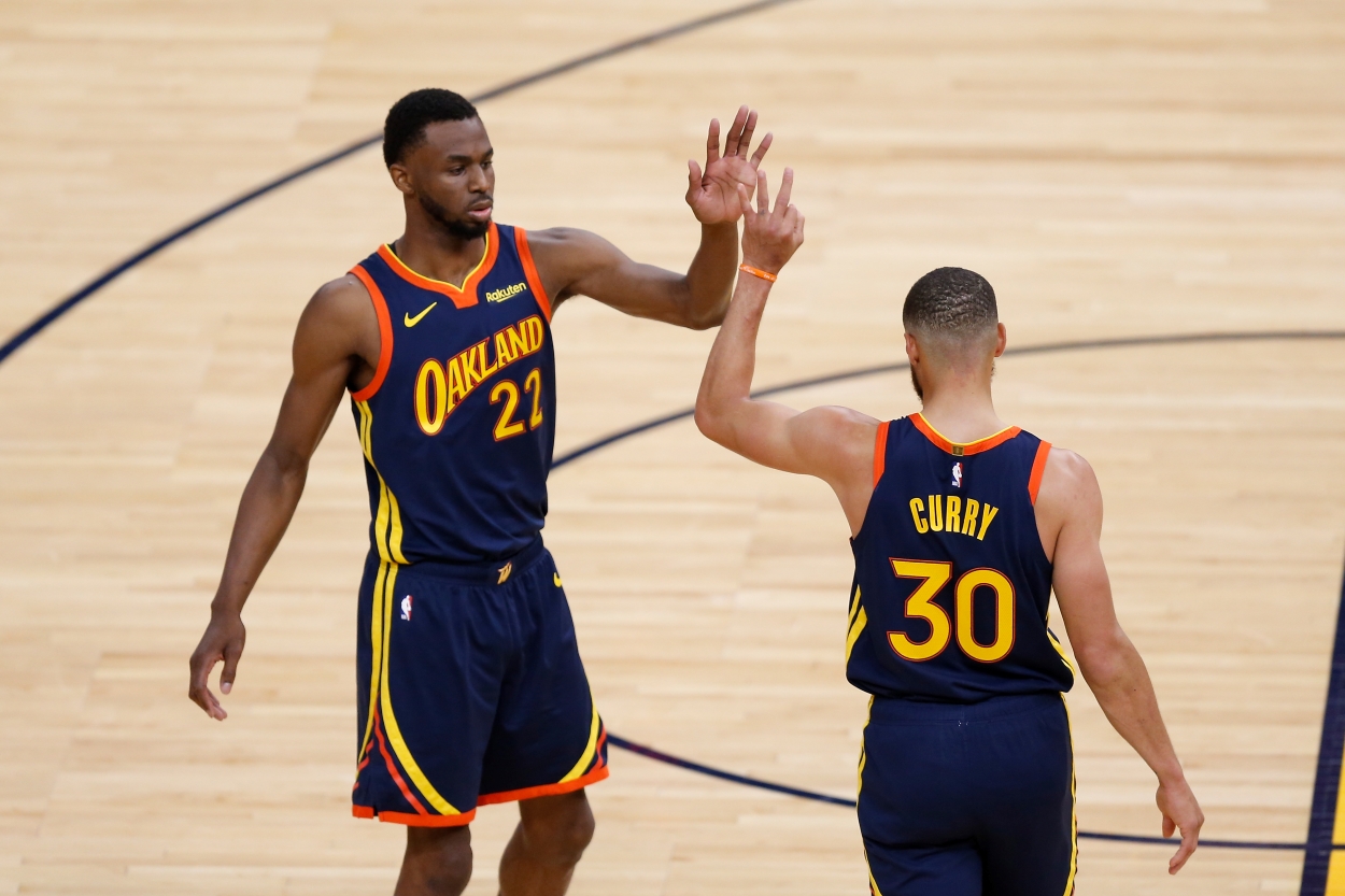 Stephen Curry and Andrew Wiggins of the Golden State Warriors high five at midcourt.