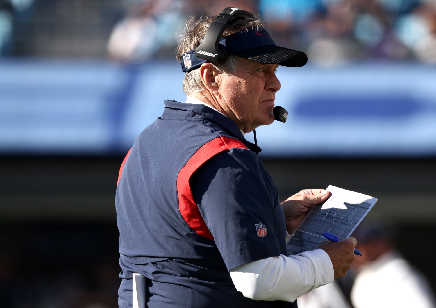 New England Patriots head coach Bill Belichick analyzes a printout of plays during a game.