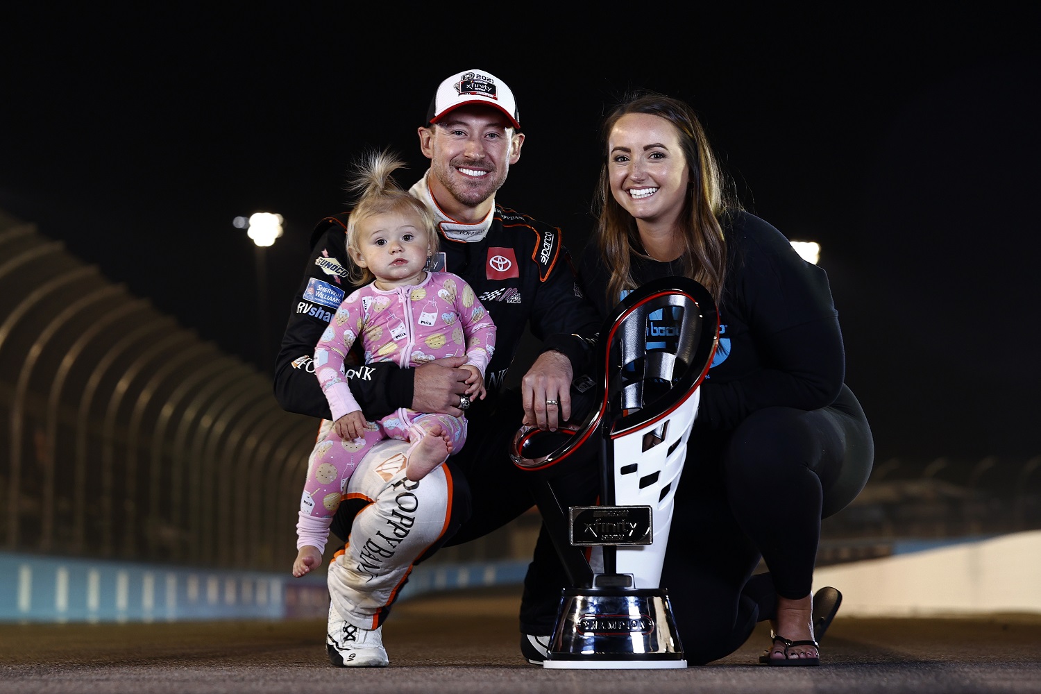 Daniel Hemric, driver of the No. 18 Toyota, poses for photos with his wife, Kenzie, and daughter, Rhen Haven, after winning the NASCAR Xfinity Series Championship at Phoenix Raceway on Nov. 6, 2021.