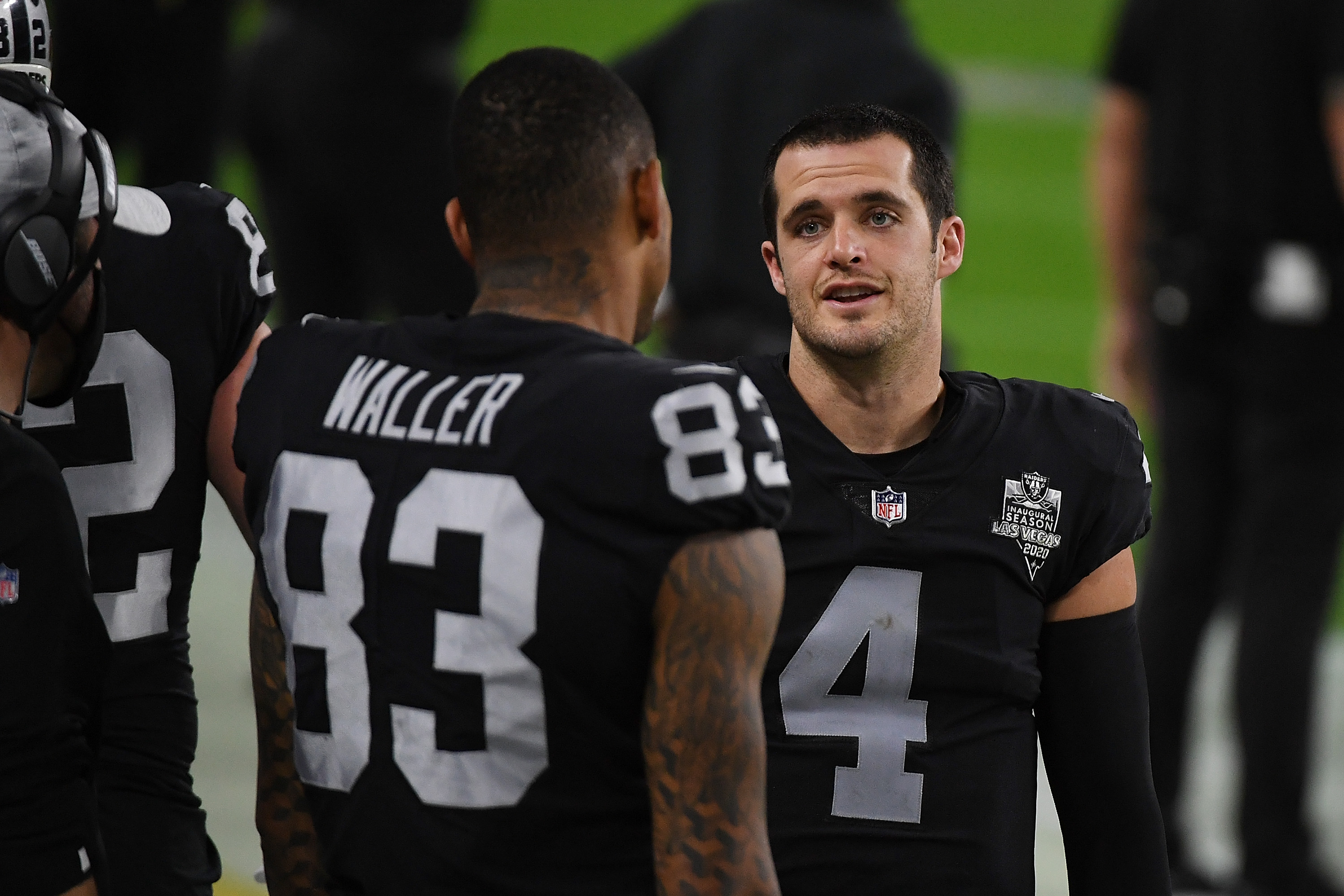Raiders teammates Darren Waller and Derek Carr talking on the sideline during a game