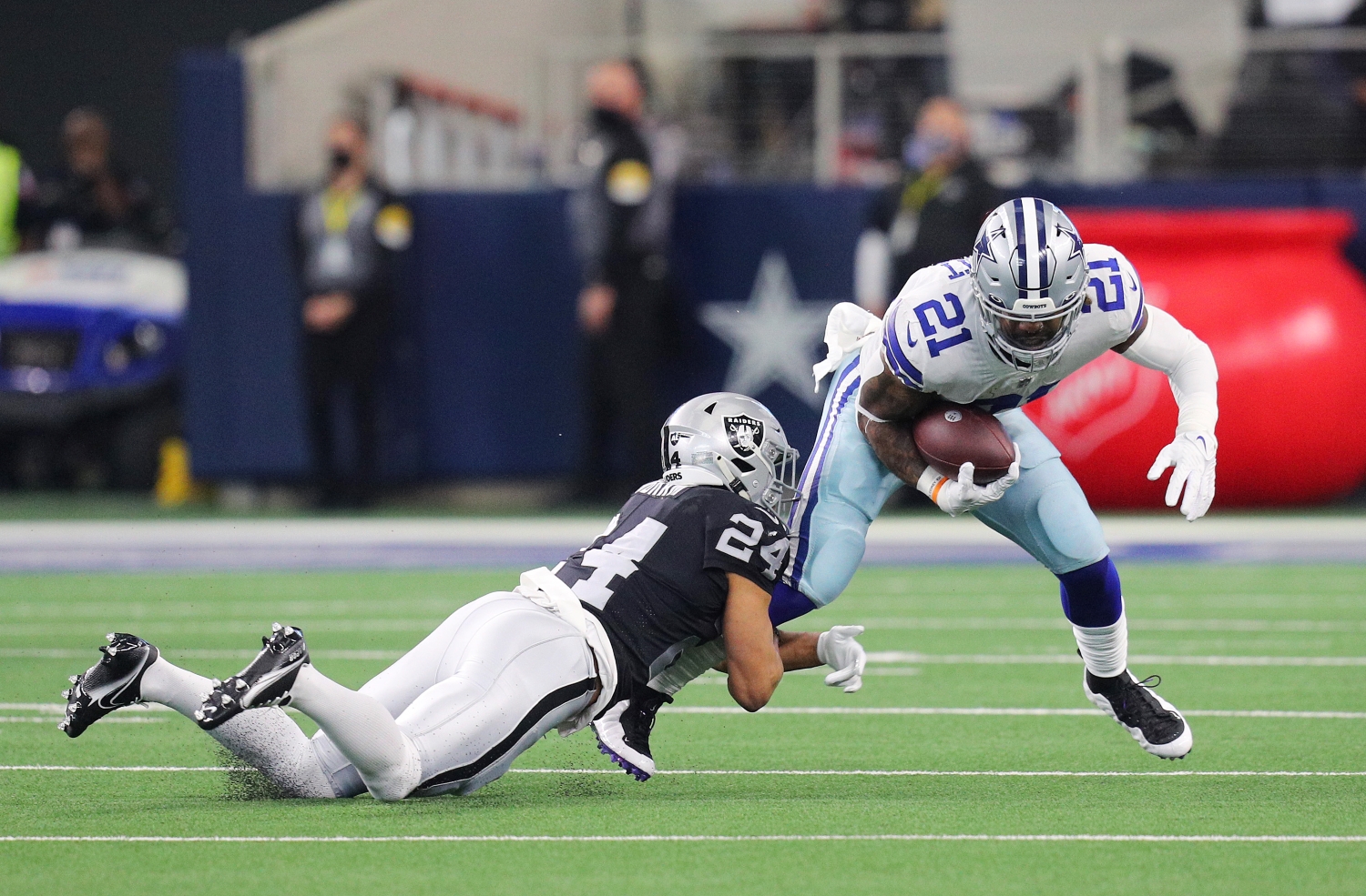 Dallas Cowboys running back Ezekiel Elliott gets tackled by Las Vegas Raiders safety Johnathan Abram.