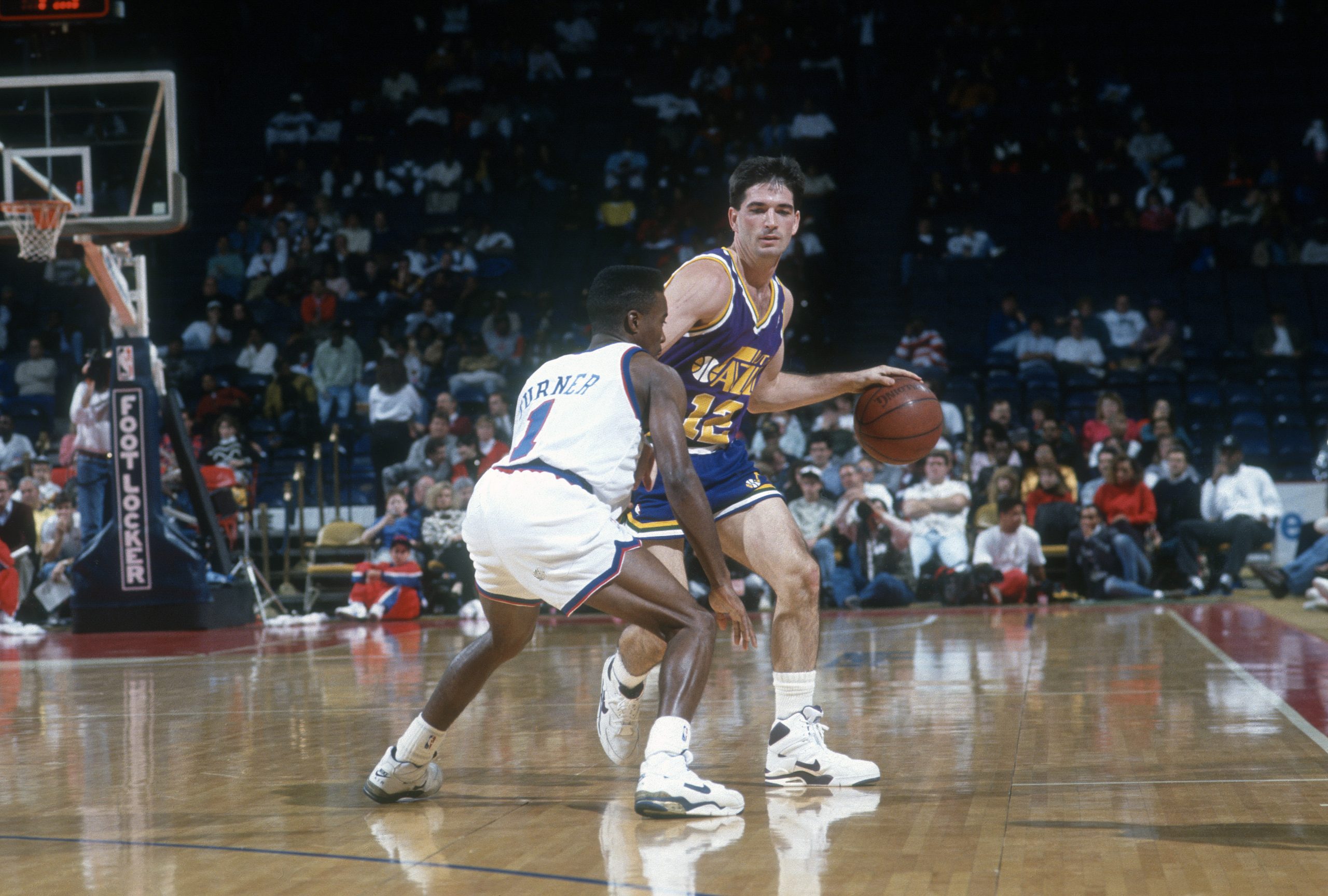 John Stockton of the Utah Jazz is defended by Andre Turner of the Washington Bullets during an NBA basketball game circa 1991.