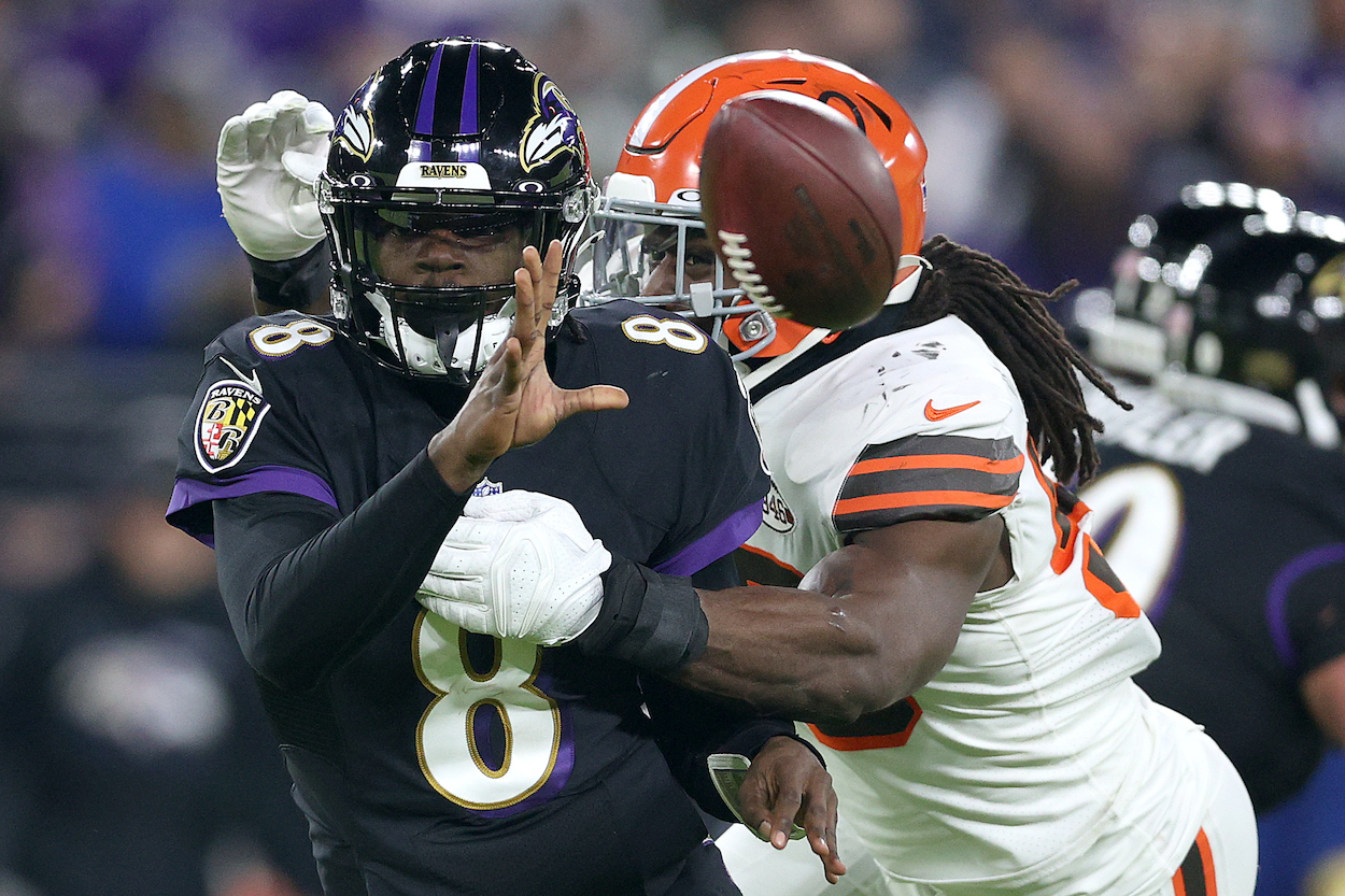 Quarterback Lamar Jackson of the Baltimore Ravens pitches the ball while being hit by defensive end Jadeveon Clowney of the Cleveland Browns at M&T Bank Stadium on November 28, 2021 in Baltimore, Maryland.