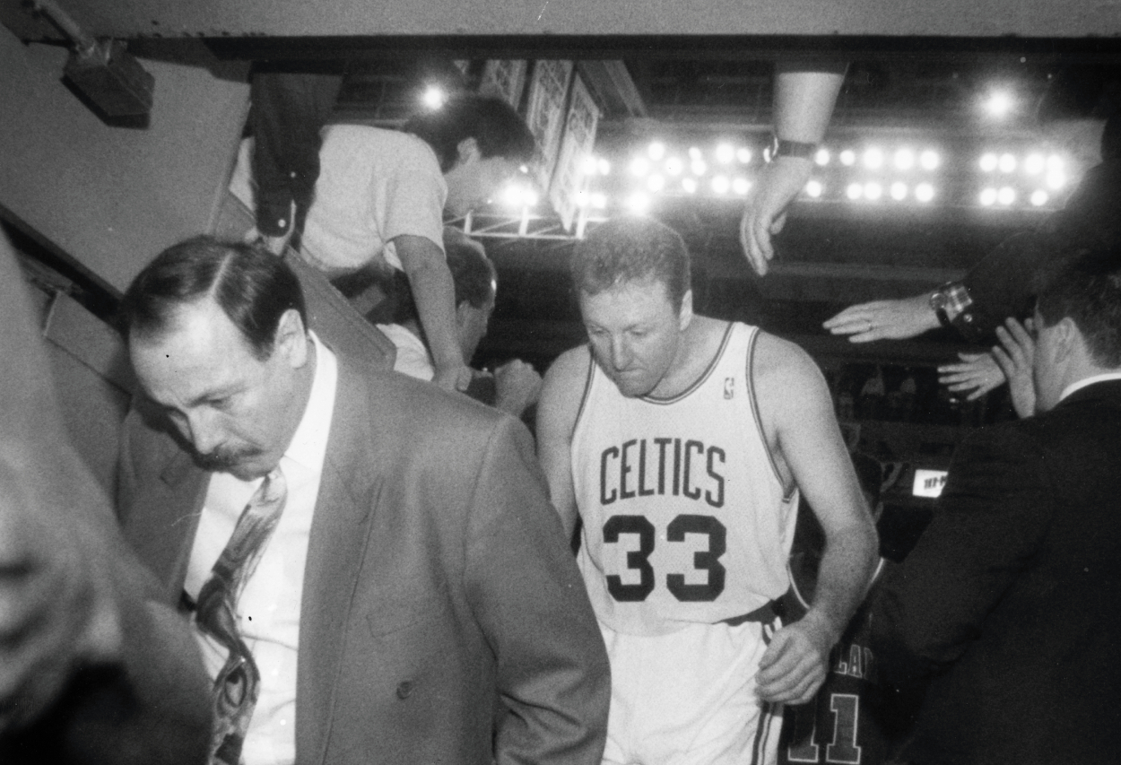 Boston Celtics head coach Chris Ford, left, and player Larry Bird duck as they exit the tunnel