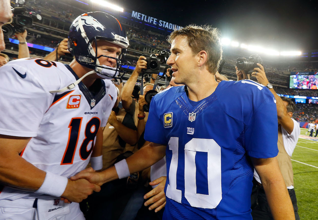 Quarterbacks Peyton Manning of the Denver Broncos and Eli Manning of the New York Giants meet after their game on September 15, 2013 at MetLife Stadium in East Rutherford, New Jersey. The Broncos defeated the Giants 41-23.