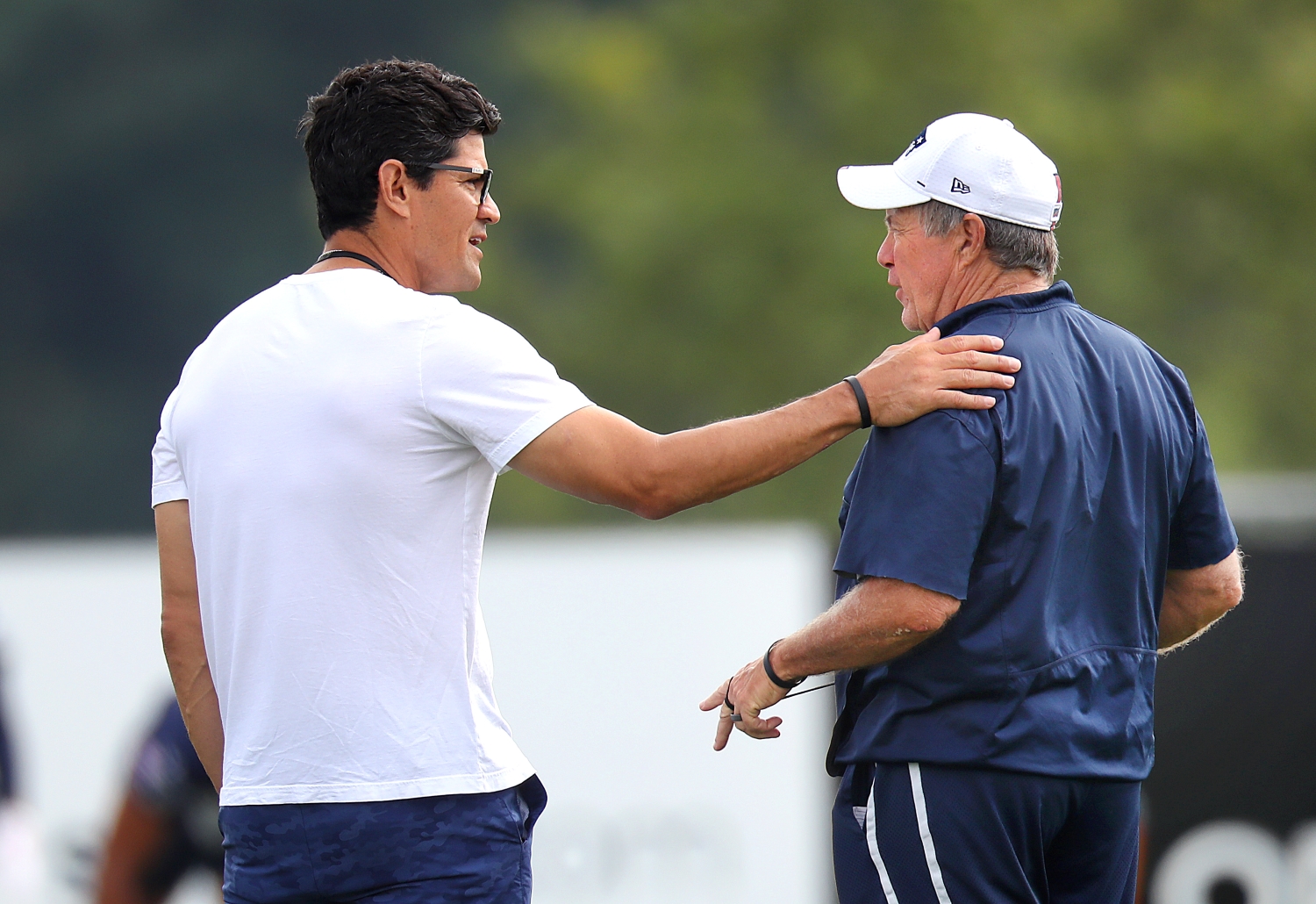 Former New England Patriots linebacker Tedy Bruschi chats with Bill Belichick during training camp practice.