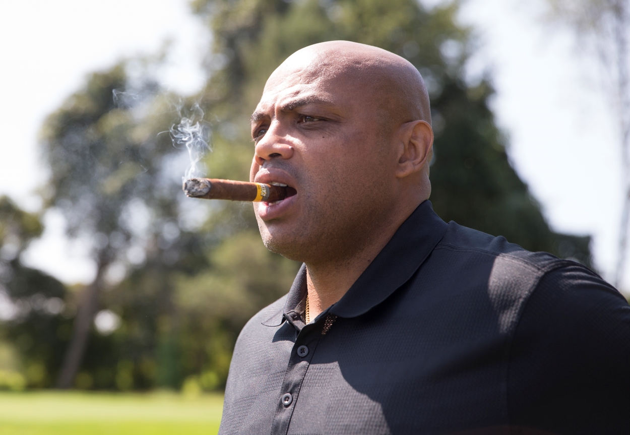 Charles Barkley puffs on a cigar during a break in a golf tournament.