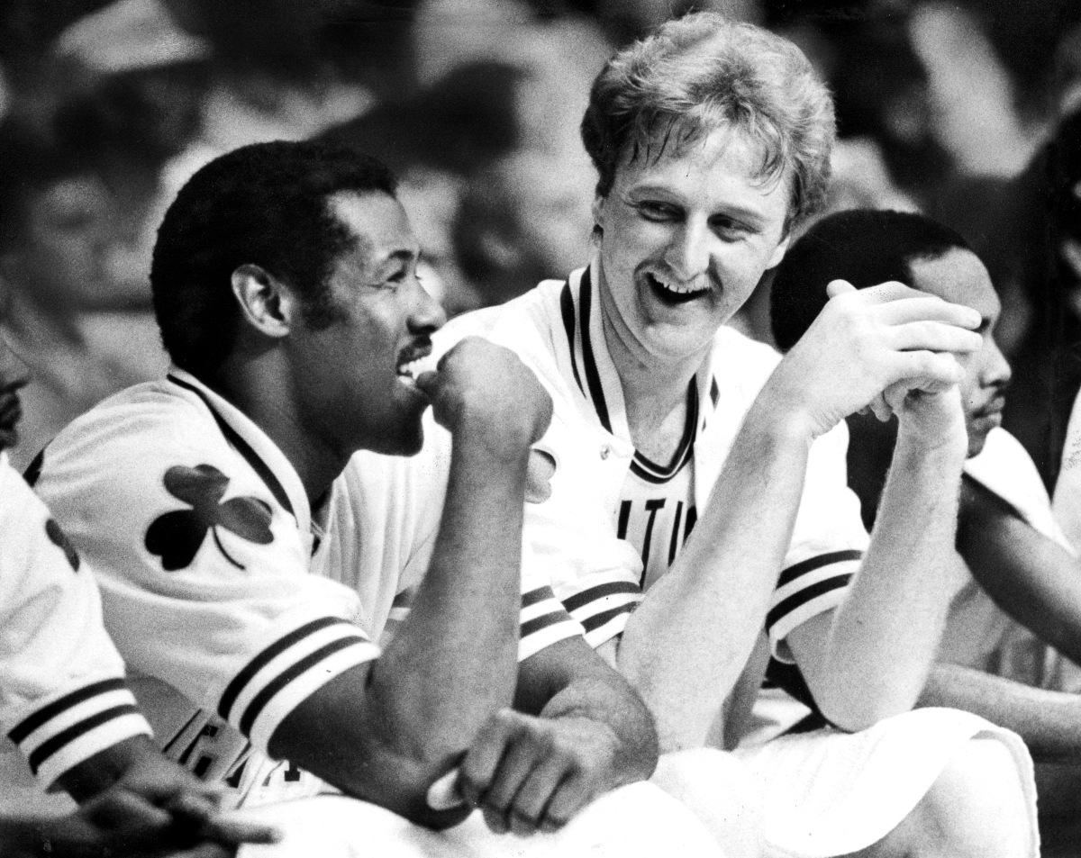 Boston Celtics teammates ML Carr and Larry Bird share a laugh on the bench.
