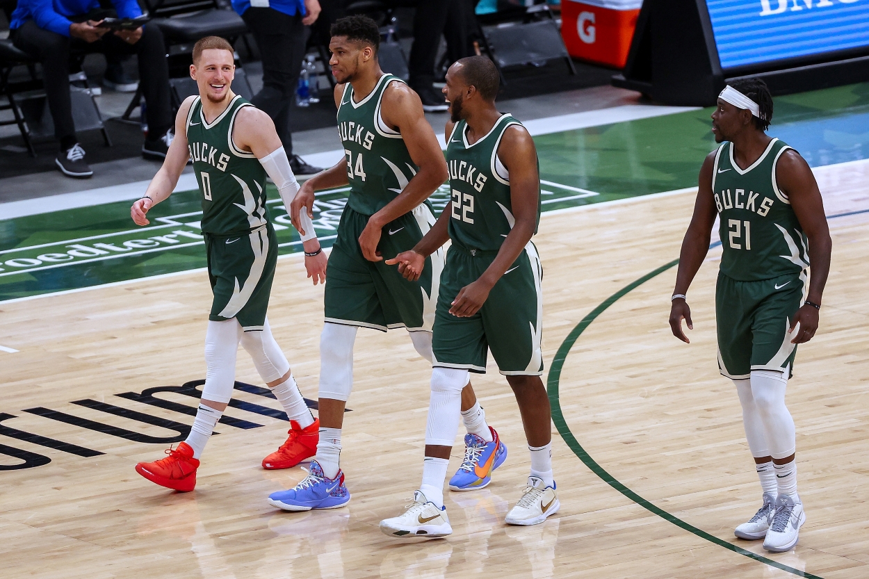 Giannis Antetokounmpo, Khris Middleton, Jrue Holiday, and Donte DiVincenzo of the Milwaukee Bucks walk across the court.
