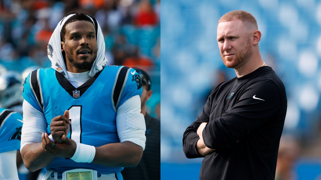 Panthers QB Cam Newton stands on the sideline; Joe Brady looks on before a game