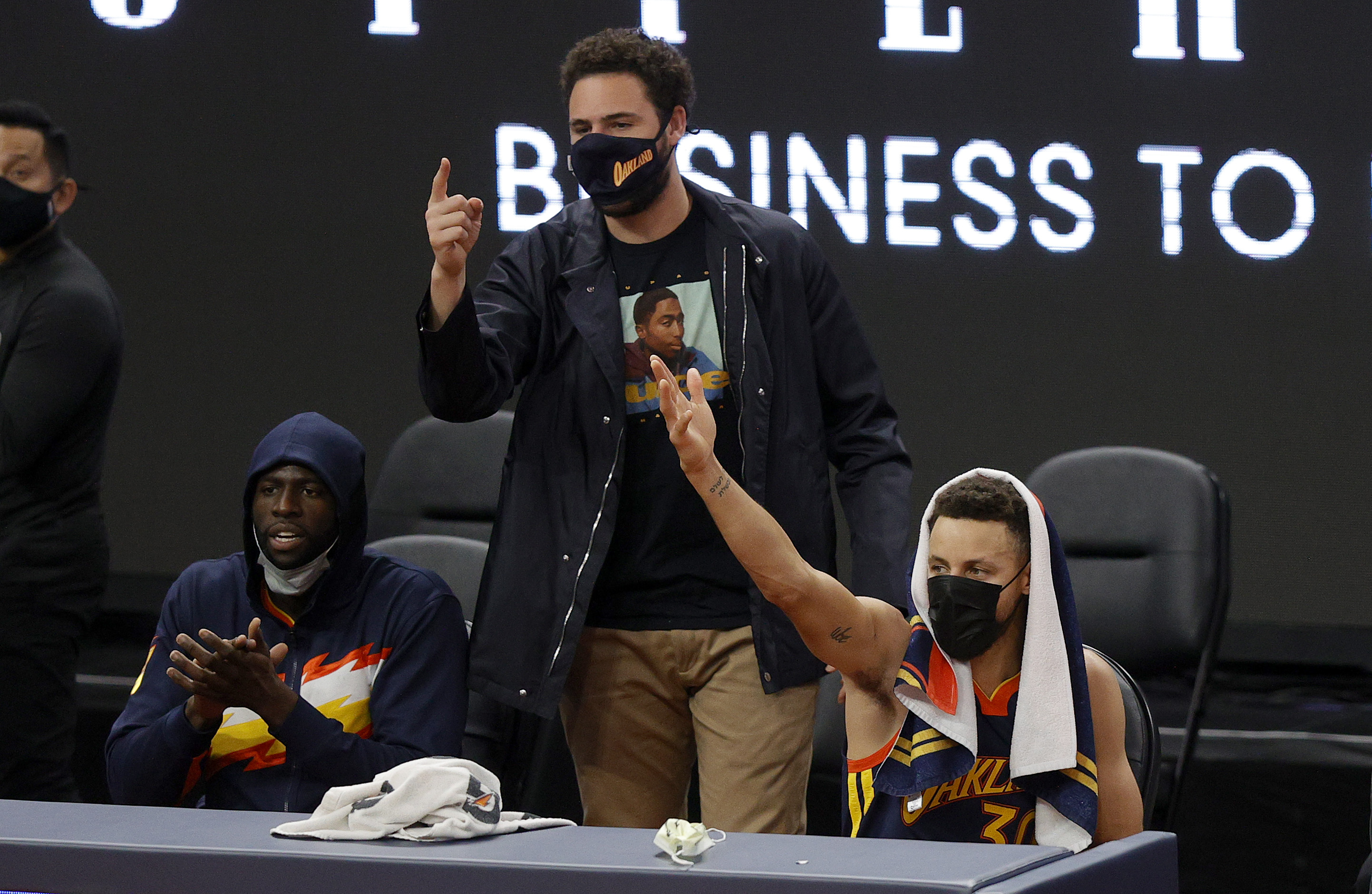 L-R: Draymond Green, Klay Thompson, and Stephen Curry of the Golden State Warriors react from the bench during an NBA game in January 2021