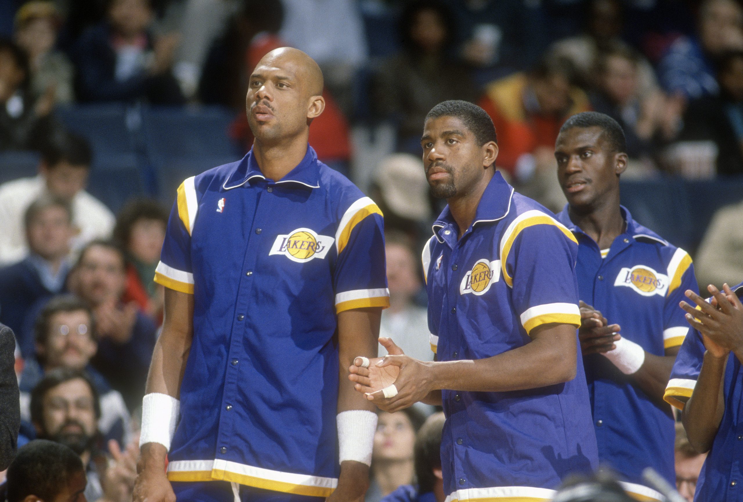 (L-R) Kareem Abdul-Jabbar, Magic Johnson, and Orlando Woolridge of the Los Angeles Lakers look on against the Indiana Pacers during an NBA basketball game circa 1988.