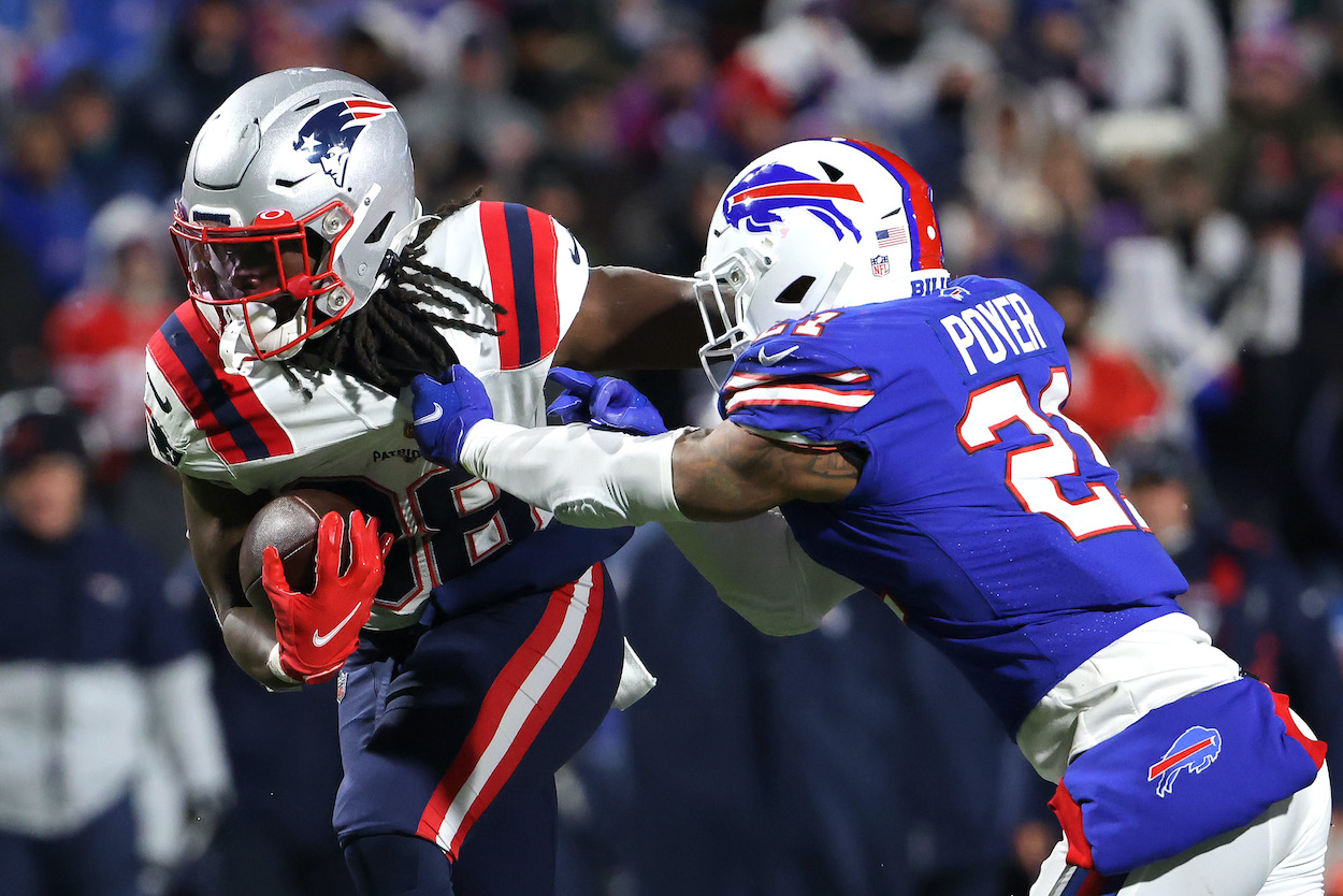 Rhamondre Stevenson of the New England Patriots carries the ball as Jordan Poyer of the Buffalo Bills — who, along with teammate Micah Hyde went off on a repoerter after the game — tackles in the third quarter of the game at Highmark Stadium on December 06, 2021 in Orchard Park, New York.
