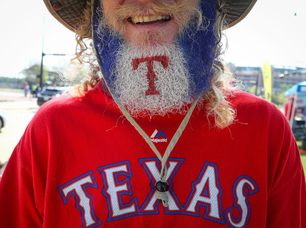 A Texas Rangers fan makes his way to the ballpark with his beard decorated with the team's logo