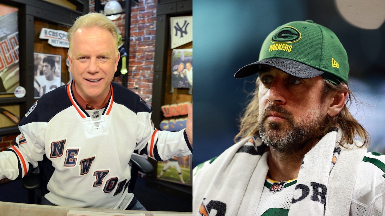 (L-R) WFAN Host Norman Julius "Boomer" Esiason. Boomer Esiason wearing his NYC Ranger jersey on is Radio show New York Manhattan 345 Hudson St. WFAN studio; Aaron Rodgers of the Green Bay Packers looks on from the sidelines during the second quarter against the Detroit Lions at Ford Field on January 09, 2022.