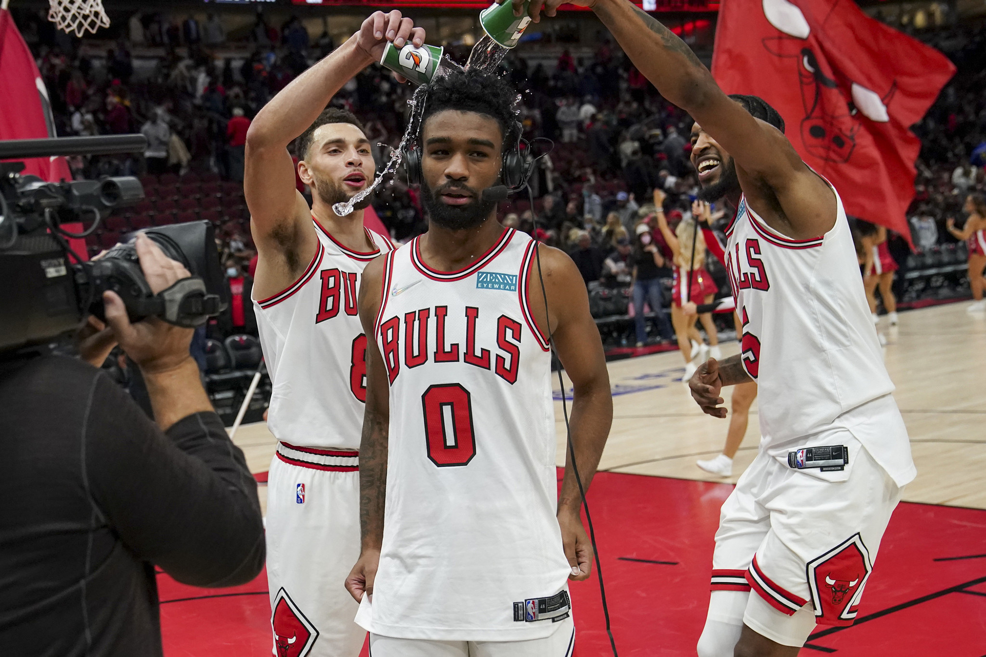 Chicago Bulls star Zach LaVine (L) and forward Derrick Jones Jr. (R) pour water on Coby White during a postgame interview