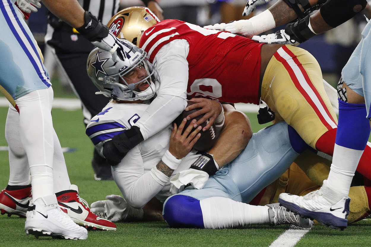 Samson Ebukam and Nick Bosa of the San Francisco 49ers sack Dak Prescott of the Dallas Cowboys during the first quarter in the NFC Wild Card Playoff game at AT&T Stadium on January 16, 2022 in Arlington, Texas.