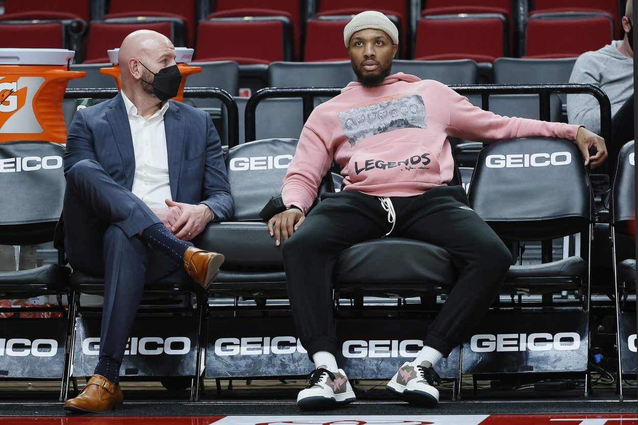 Injured Portland Trail Blazers guard Damian Lillard talks to interim general manager Joe Cronin before an NBA game against the Miami Heat