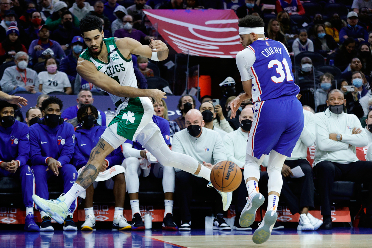 Jayson Tatum of the Boston Celtics reaches for a loose ball past Seth Curry of the Philadelphia 76ers.