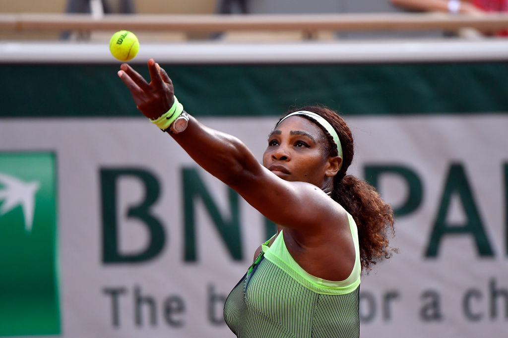 Serena Williams tosses a tennis ball as she prepares to serve during the 2021 French Open.