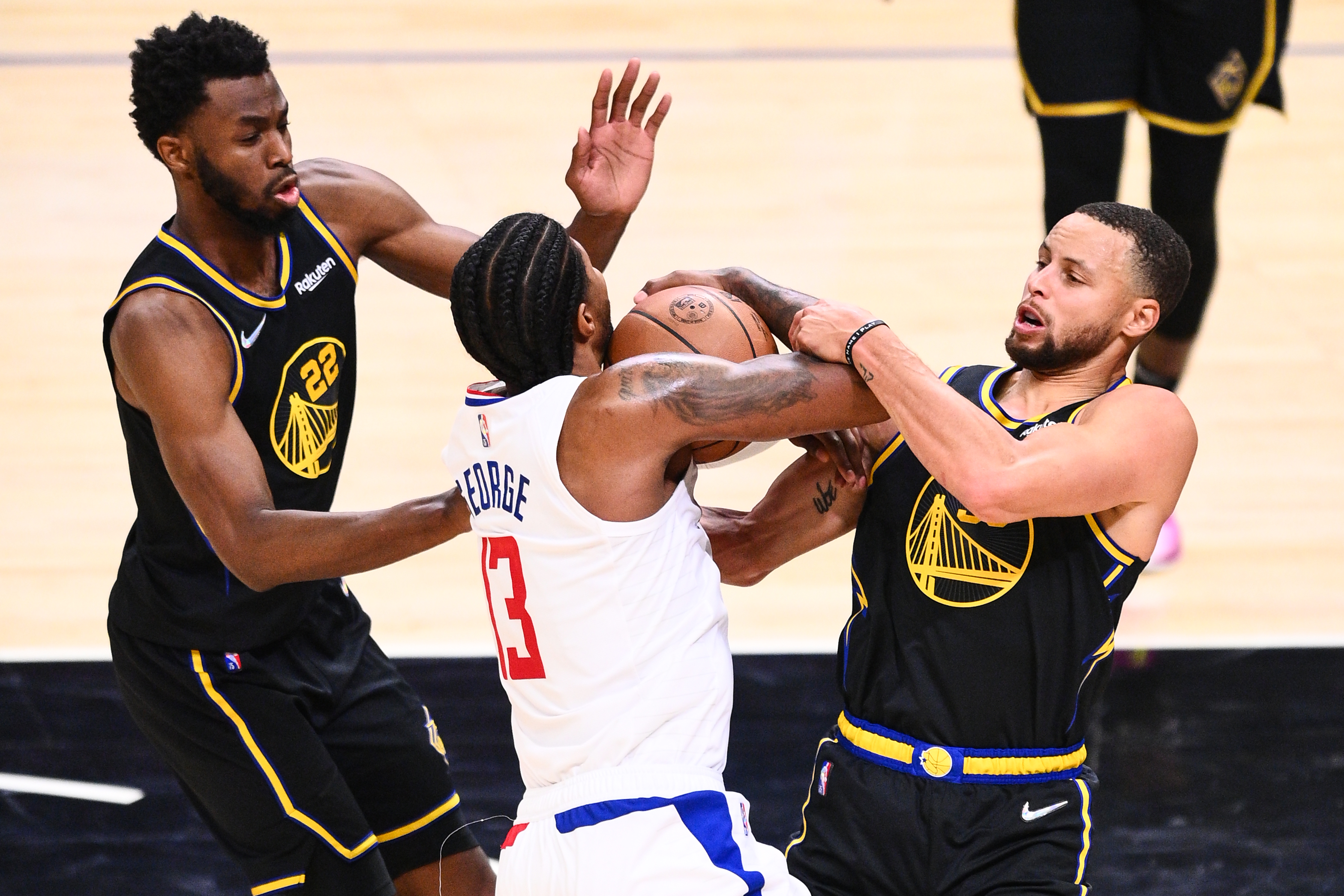 Golden State Warriors stars Stephen Curry and Andrew Wiggins trap Los Angeles Clippers forward Paul George during an NBA game in November 2021