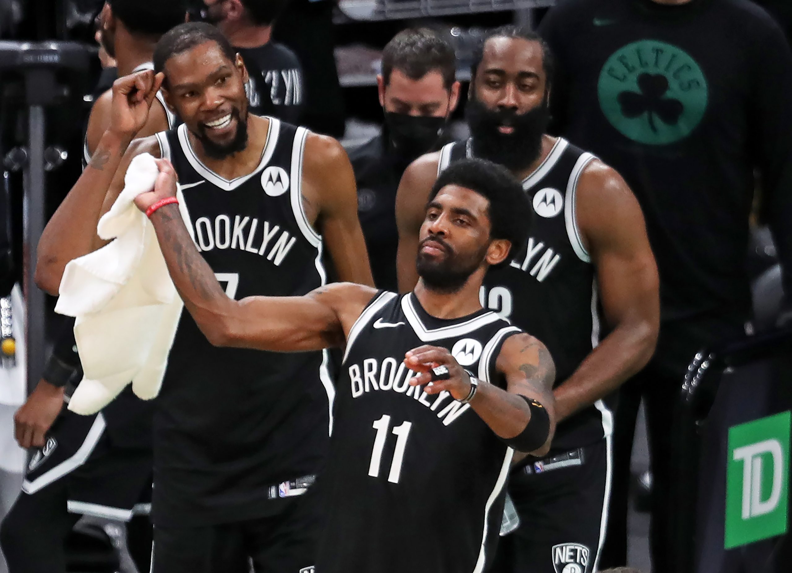 Brooklyn Nets star guard Kyrie Irving waves a towel in celebration alongside teammates Kevin Durant and James Harden during a game at Boston's TD Garden on May 30, 2021.