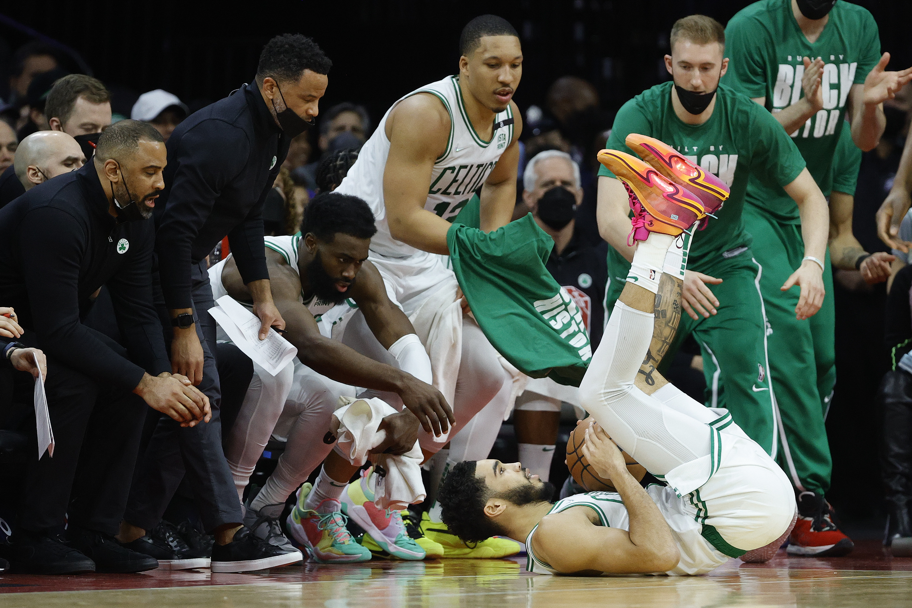 Boston Celtics star Jayson Tatum #0 falls to the floor as Jaylen Brown #7 and other teammates reach to help him up during an NBA game against the Philadelphia 76ers in February 2022