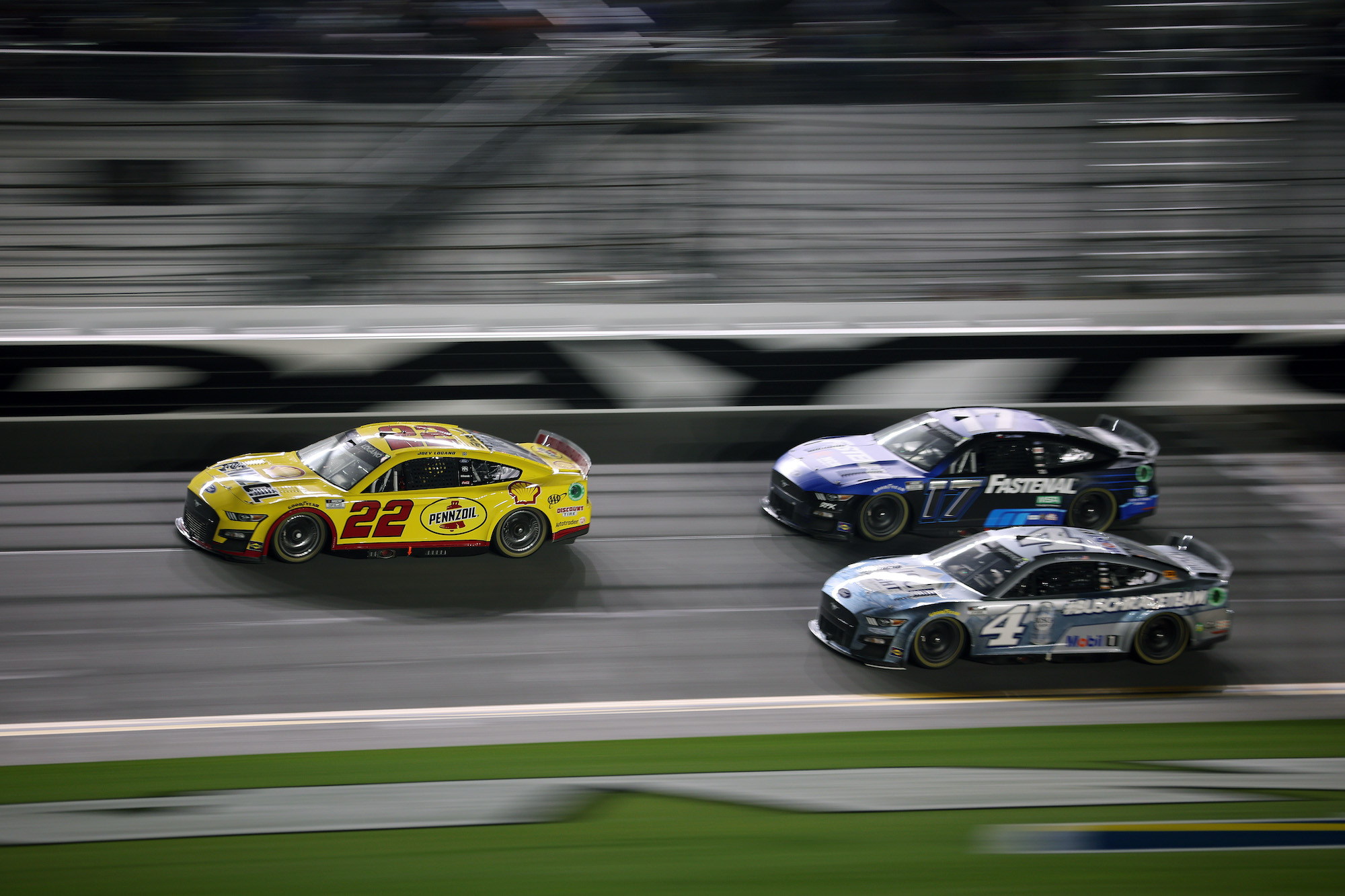 Joey Logano races Chris Buescher and Kevin Harvick