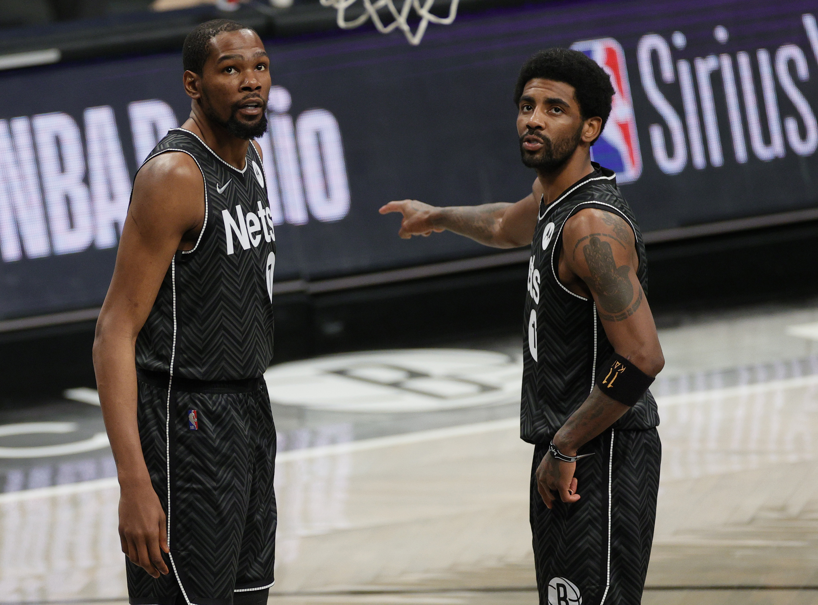 Brooklyn Nets stars Kyrie Irving (R) and Kevin Durant talk during an NBA game against the Phoenix Suns in April 2021