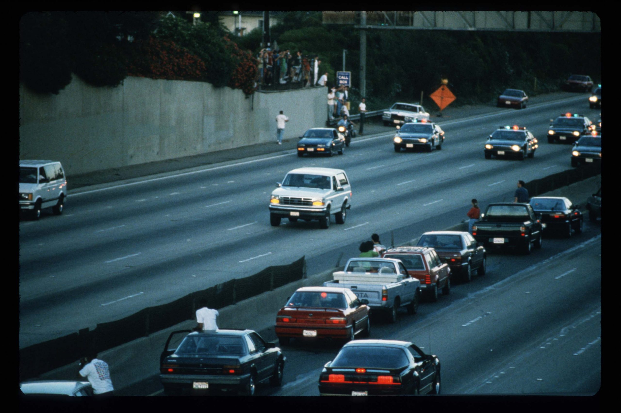 Motorists stop and wave as police cars pursue the Ford Bronco (white, R) driven by Al Cowlings, carrying fugitive murder suspect O.J. Simpson.