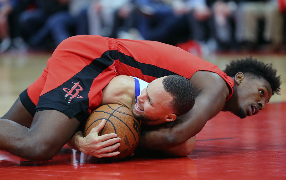 Golden State Warriors superstar guard Stephen Curry (bottom) and Houston Rockets forward Jae'Sean Tate (top) scramble for a loose ball during the fourth quarter at Toyota Center on January 31, 2022 in Houston, Texas.