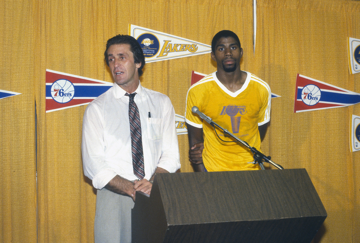 Former Los Angeles Lakers head coach Pat Riley stands next to Magic Johnson and addresses the media.