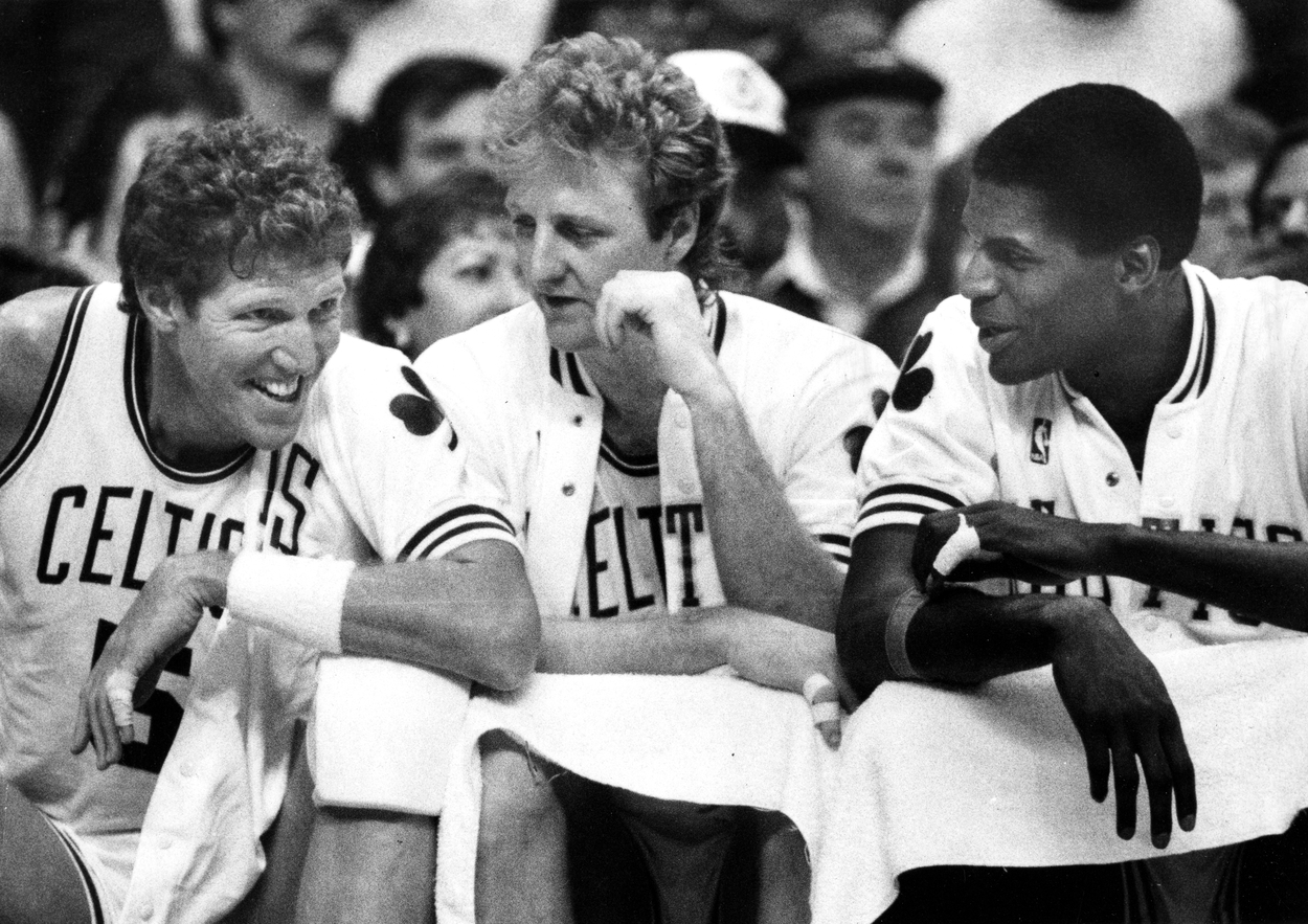 Boston Celtics stars Bill Walton, Larry, and Robert Parish talk on the bench.