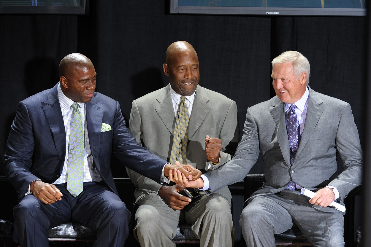 Los Angeles Lakers legends Magic Johnson, James Worthy, and Jerry West sit side-by-side.