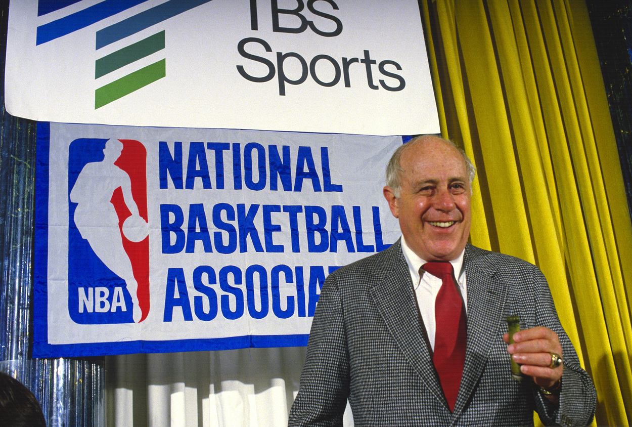 Boston Celtics President Red Auerbach smiles with a cigar in hand.