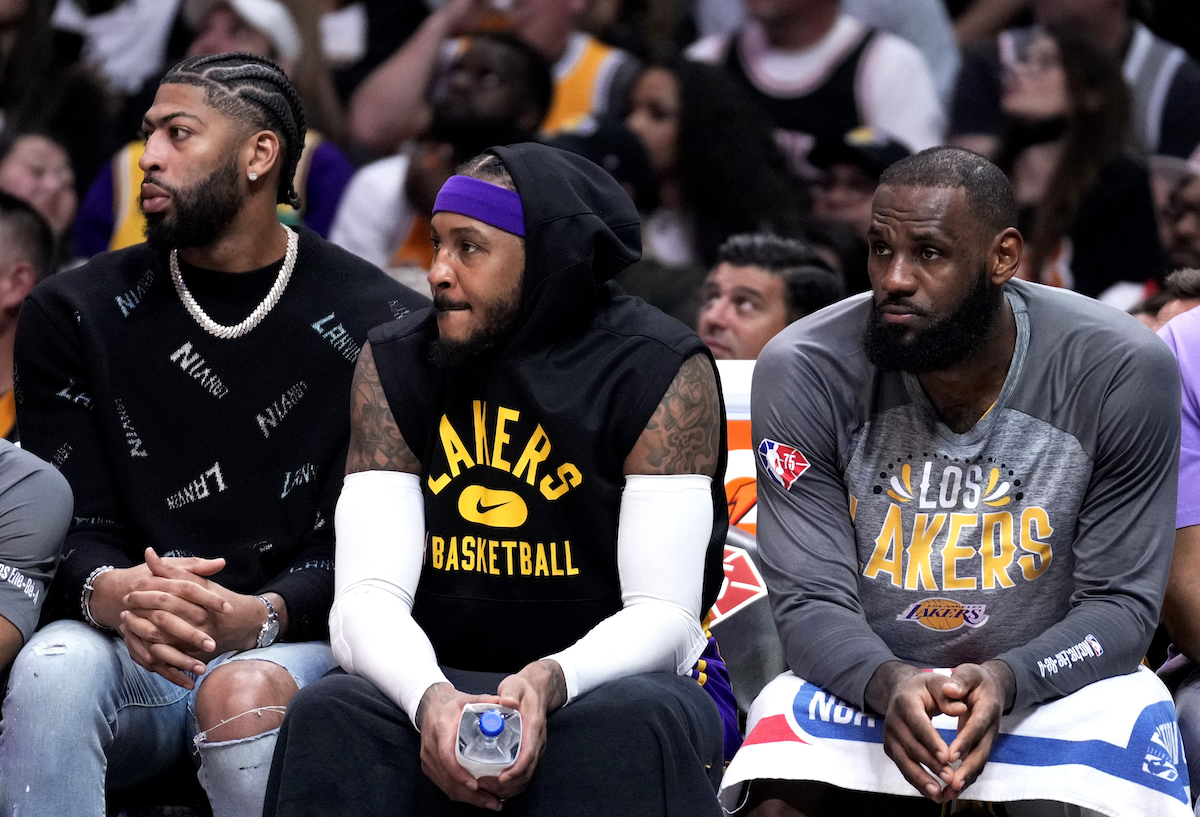 Anthony Davis, Carmelo Anthony, and LeBron James of the Los Angeles Lakers look on from the bench against the Clippers