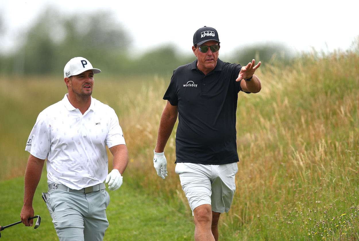 Bryson DeChambeau and Phil Mickelson chat as they walk down the 7th fairway at The Open