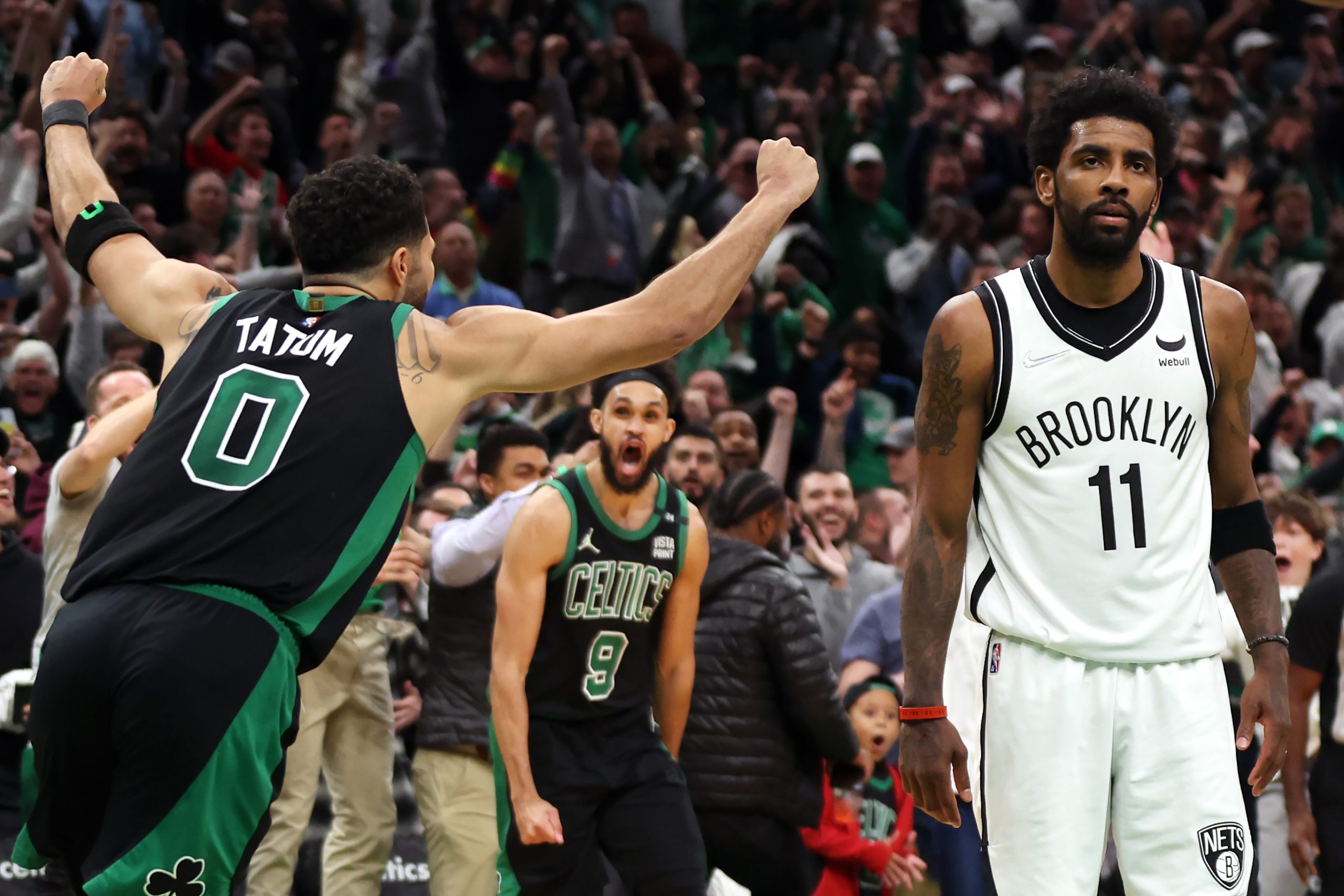 Jayson Tatum of the Boston Celtics celebrates the game winning basket as Kyrie Irving of the Brooklyn Nets looks on.