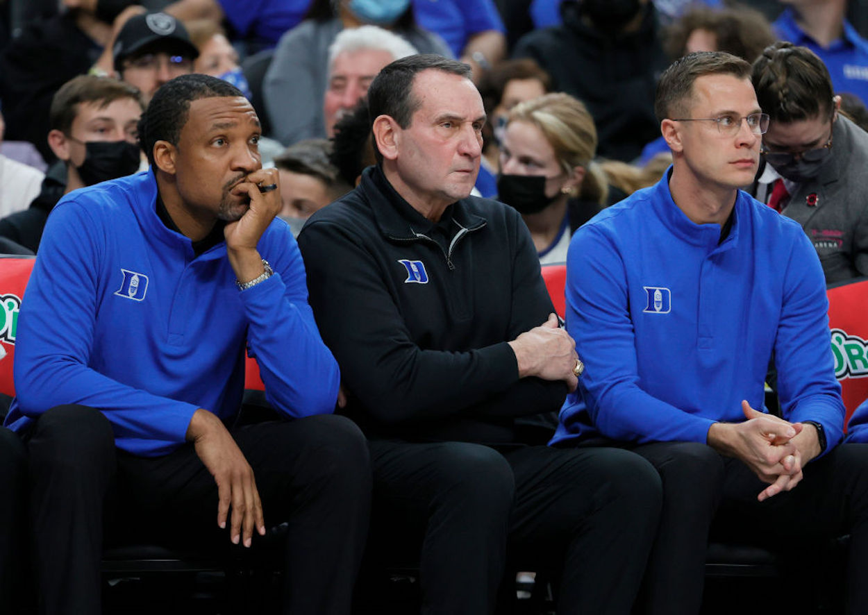 Mike Krzyzewski sits on the Duke bench with the rest of his coaching staff.