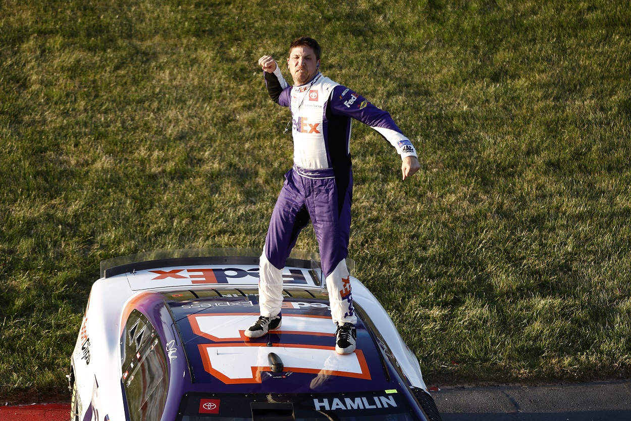 Denny Hamlin stands on his No. 11 car after winning the 2022 NASCAR Cup Series Toyota Owners 400
