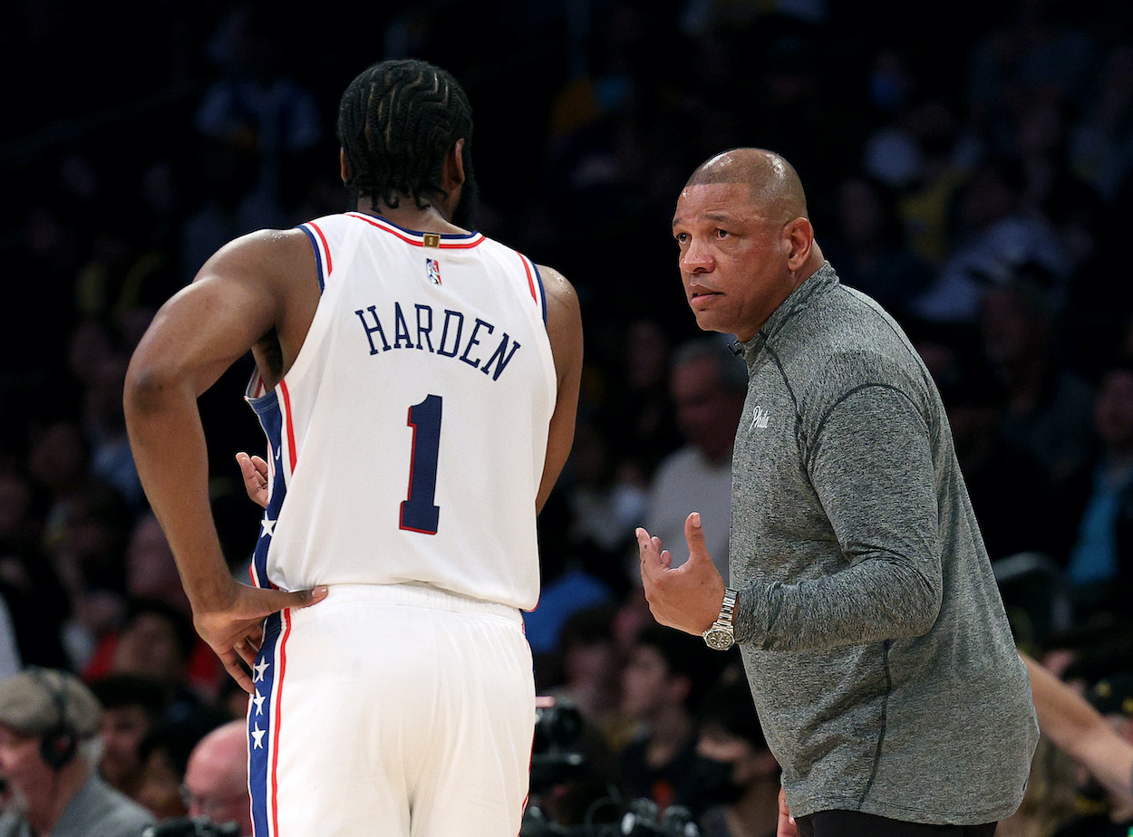James Harden speaks with Doc Rivers on the court.