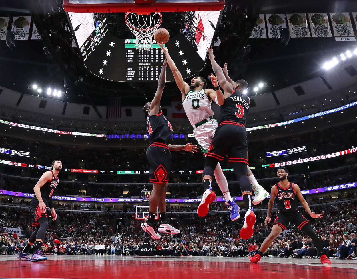 Jayson Tatum of the Boston Celtics shoots between Patrick Williams #44 and Tristan Thompson #3 of the Chicago Bulls.