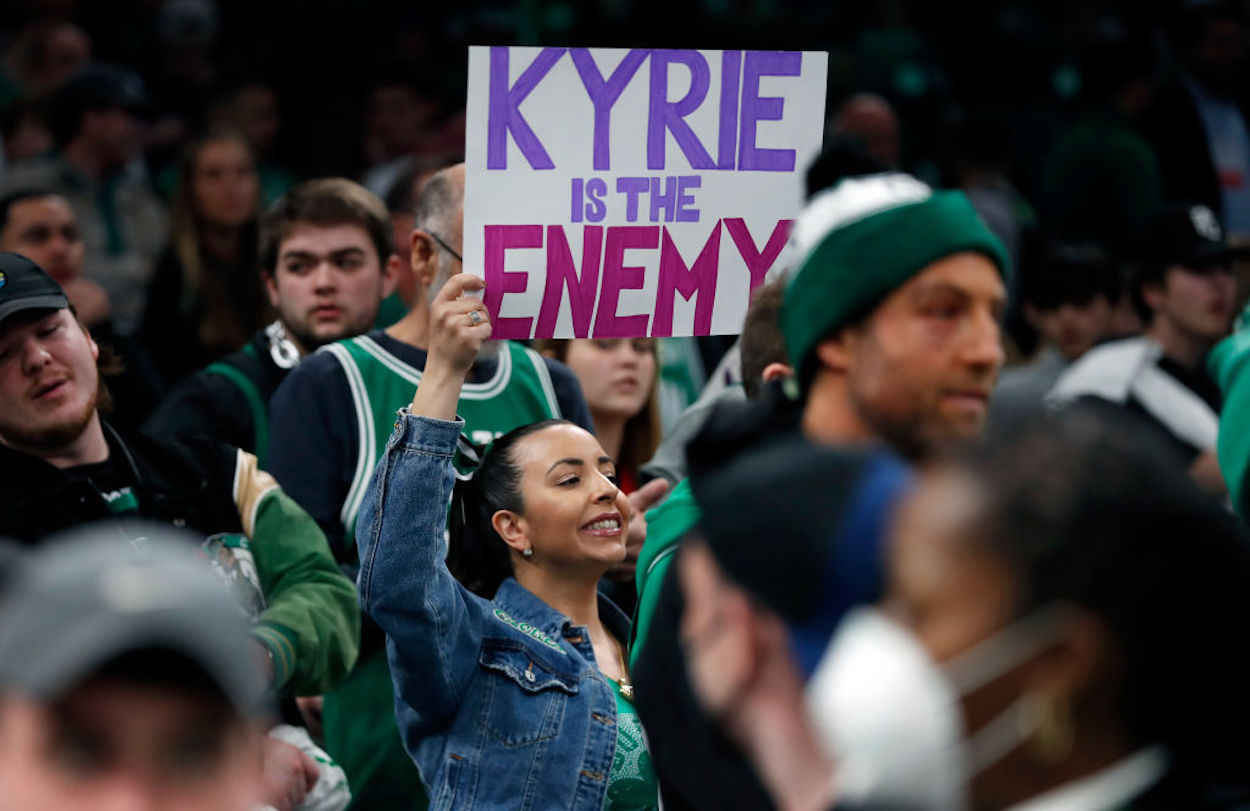 A Boston Celtics fan holds a sign calling Kyrie Irving "the enemy."