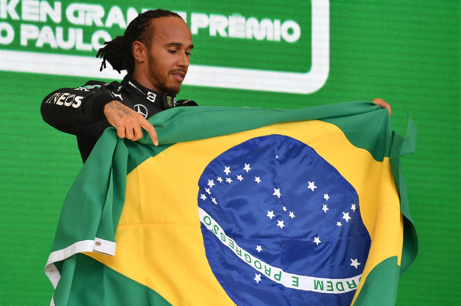 Mercedes' British driver Lewis Hamilton displays a Brazilian flag as he celebrates on the podium after winning Brazil's Formula One Sao Paulo Grand Prix at the Autodromo Jose Carlos Pace on Nov. 14, 2021.
